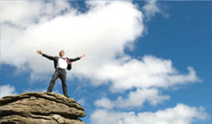 Man standing on cliff with arms out.